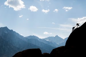 An image of a person climbing a mountain and helping others - WorkspaceDNA Resources